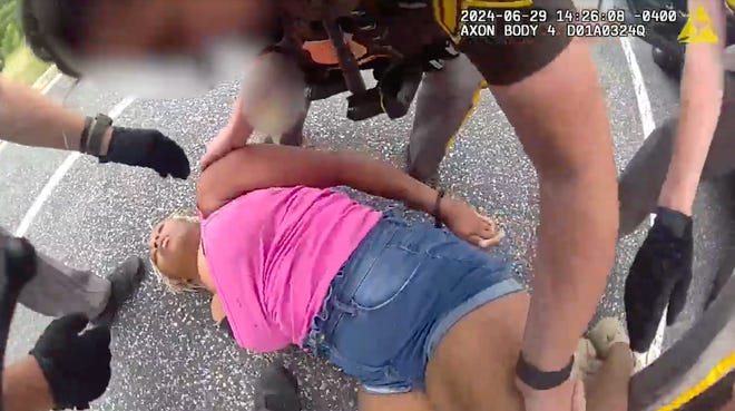 A woman, whose arrest late last month was recorded by a bystander and circulated quickly across social media, refuses to get her legs inside a police vehicle after being handcuffed.